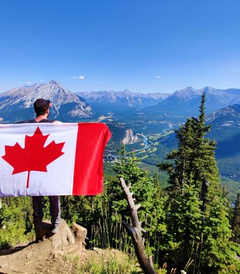 immigration-belonging-identity-vancouver-counselling An immigrant holding a Canadian flag in Vancouver on a mountain