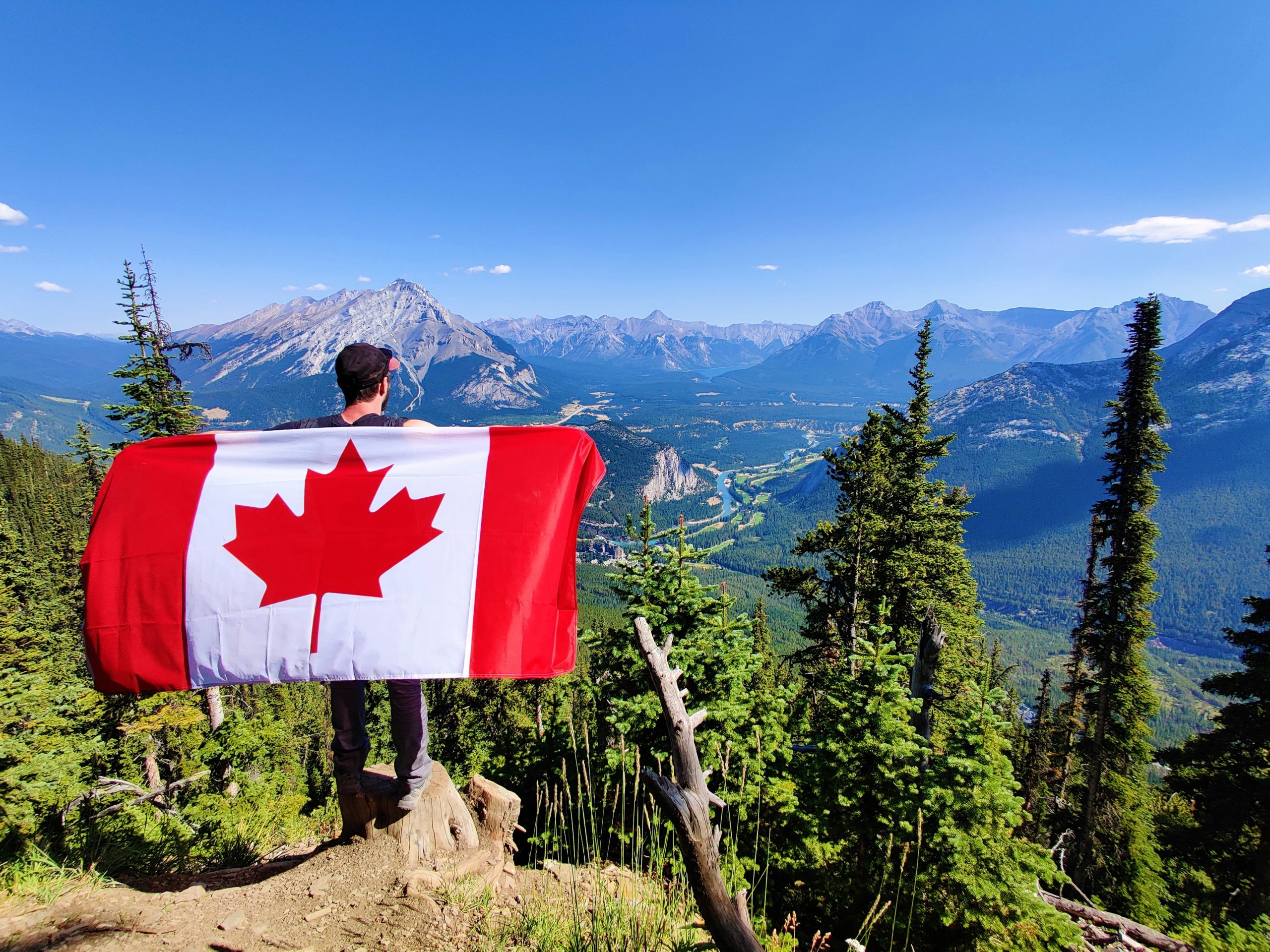 An immigrant holding a Canadian flag in Vancouver on a mountain